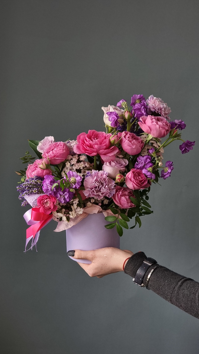 Crop lady showing decorated bouquet of fresh delicate flowers in black studio